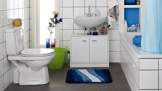 Cluttered bathroom seen before renovation, with floor-standing WC and exposed cistern Cluttered bathroom seen before renovation, with floor-standing WC and exposed cistern